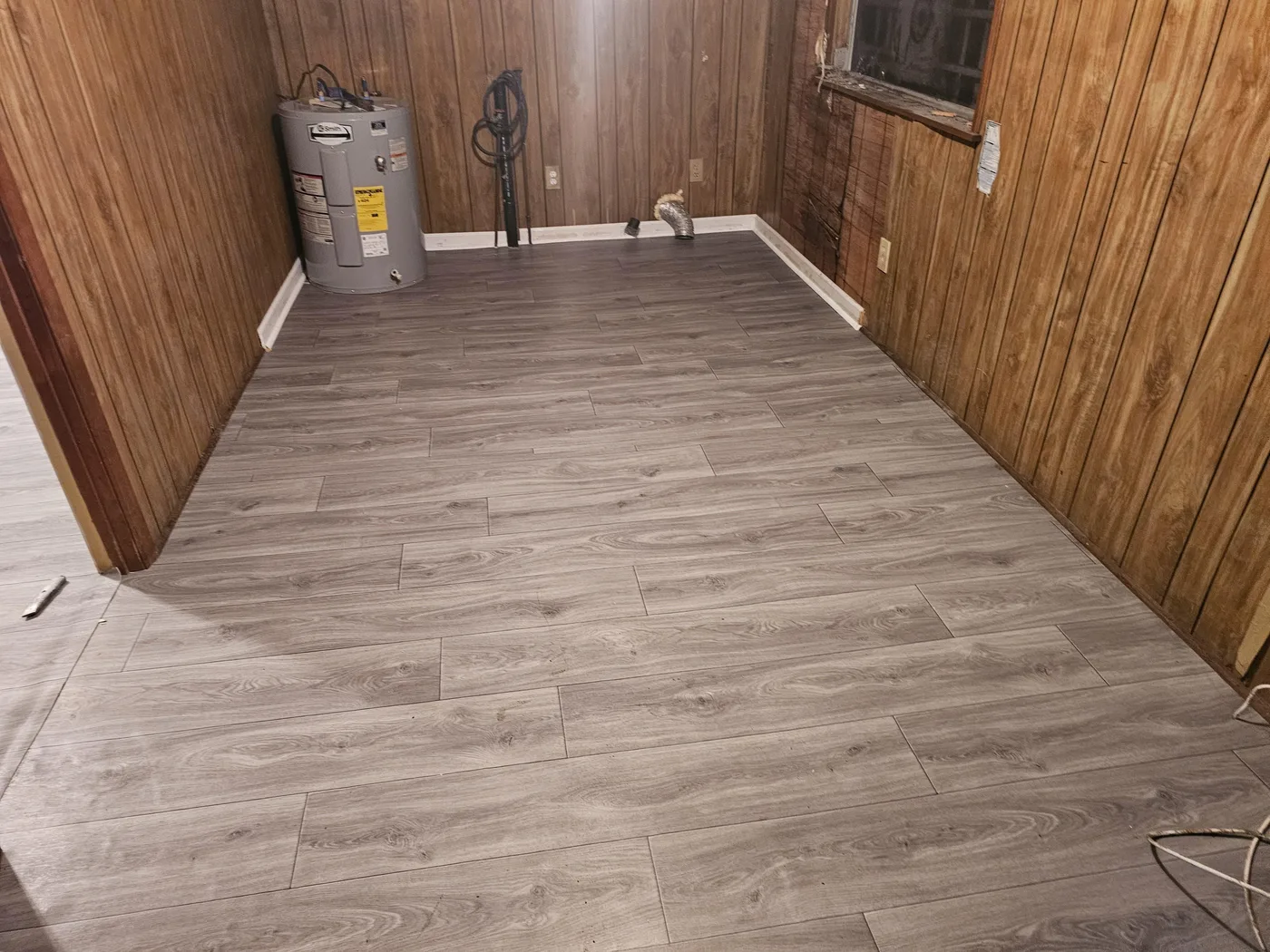 New luxury vinyl plank floor in a wood-paneled room
