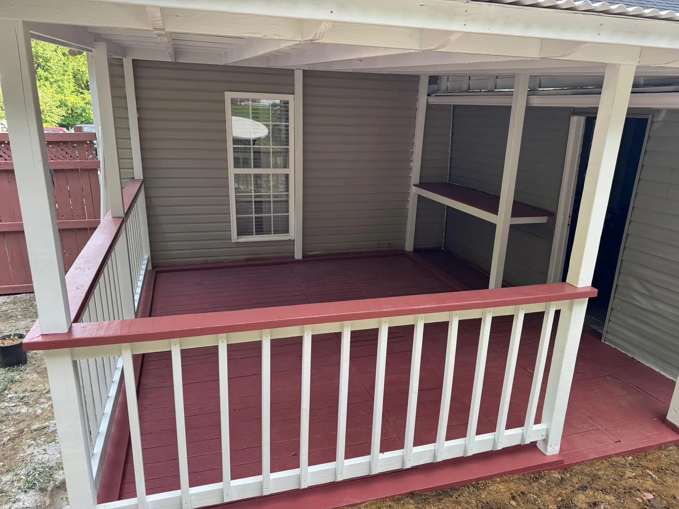 Covered porch we built with white railings and red-painted floor