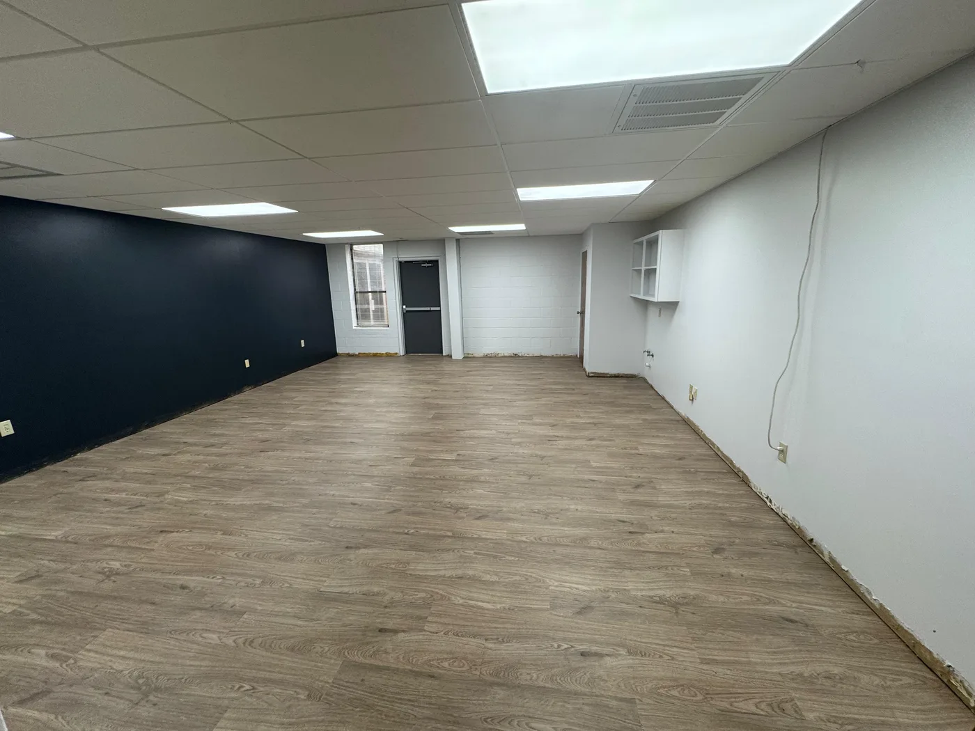 Open room remodeled with new flooring and navy accent wall